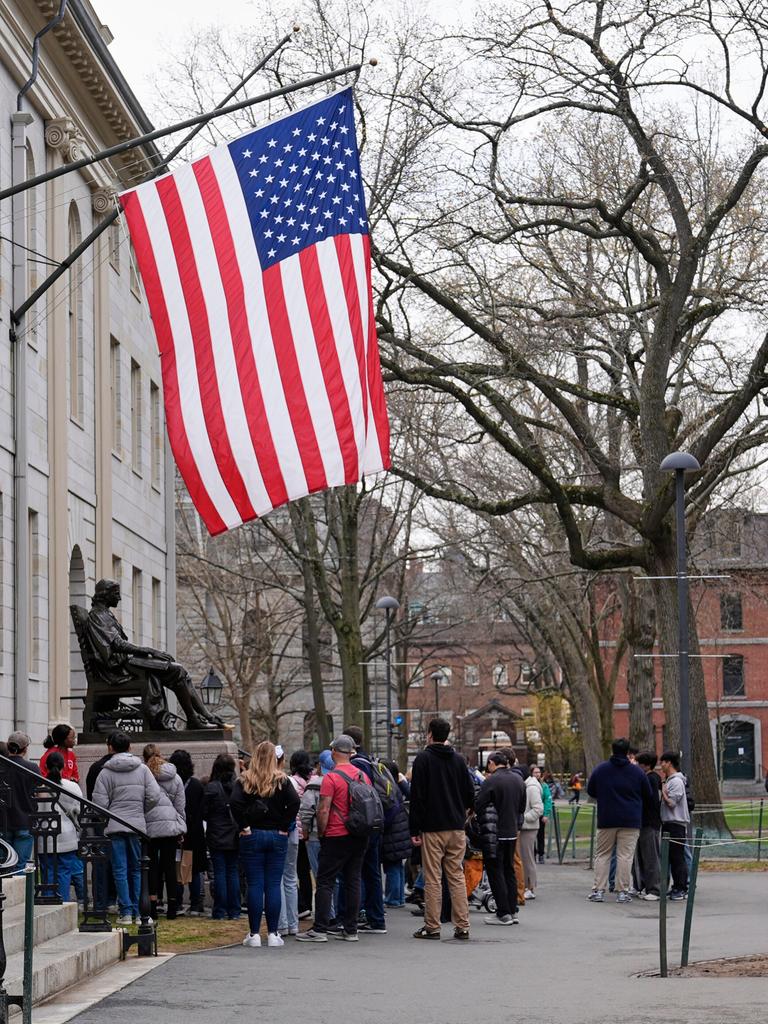 Besucher stehen unter der US-Flagge an der Statue von John Harvard an der Harvard Universität in Cambridge in den USA. 