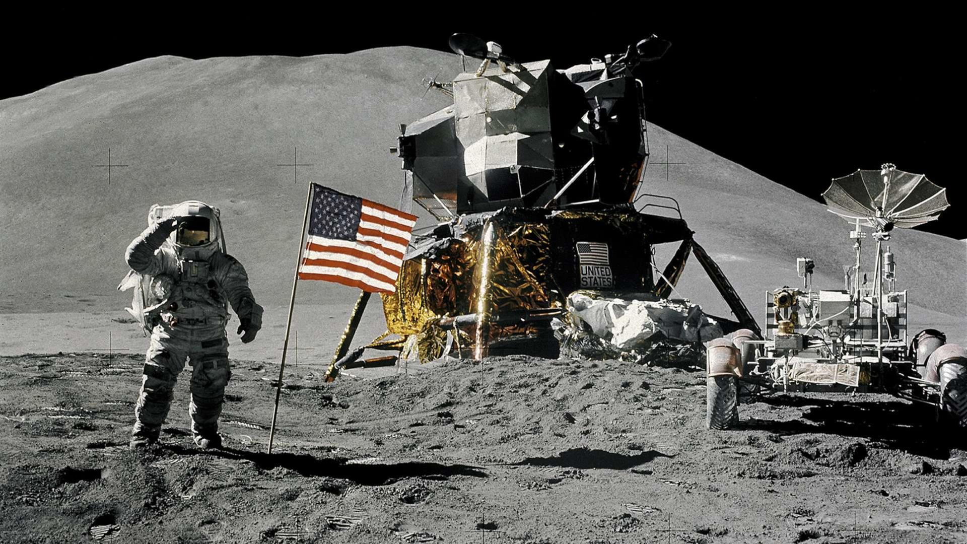 Bei Apollo 17 (im Dezember 1972) waren zum letzten Mal Menschen auf dem Mond. Auf dem Foto sieht man einen Astronauten, eine US-Flagge und ein Mondfahrzeug.