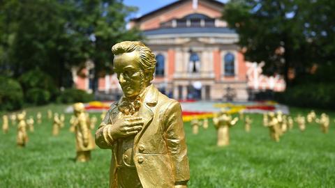 Goldene Skulpturen von Richard Wagner stehen bei den Wagnerfestspielen 2025 auf dem Grünen Hügel vor dem Festspielhaus.
