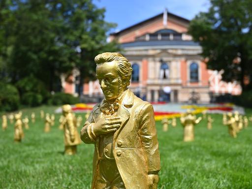 Goldene Skulpturen von Richard Wagner stehen bei den Wagnerfestspielen 2025 auf dem Grünen Hügel vor dem Festspielhaus.