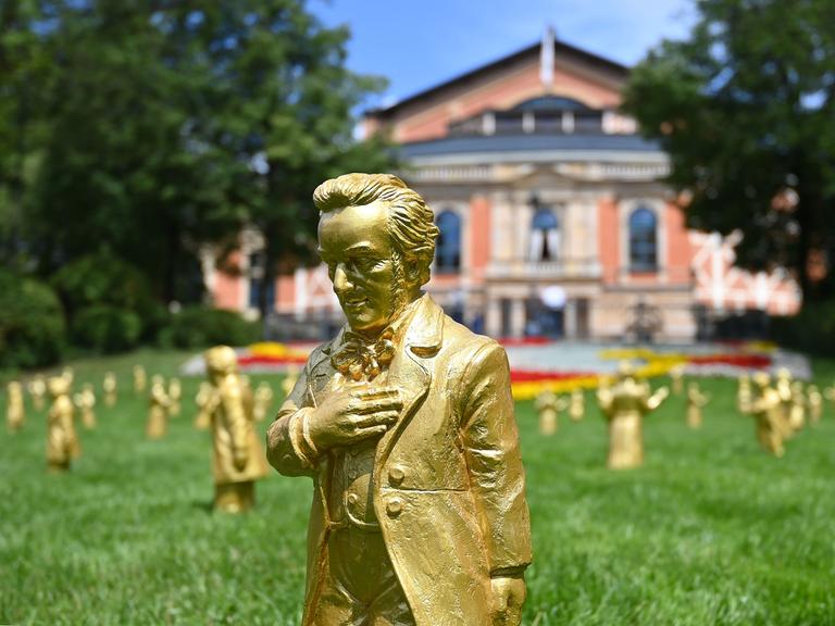 Goldene Skulpturen von Richard Wagner stehen bei den Wagnerfestspielen 2025 auf dem Grünen Hügel vor dem Festspielhaus.
