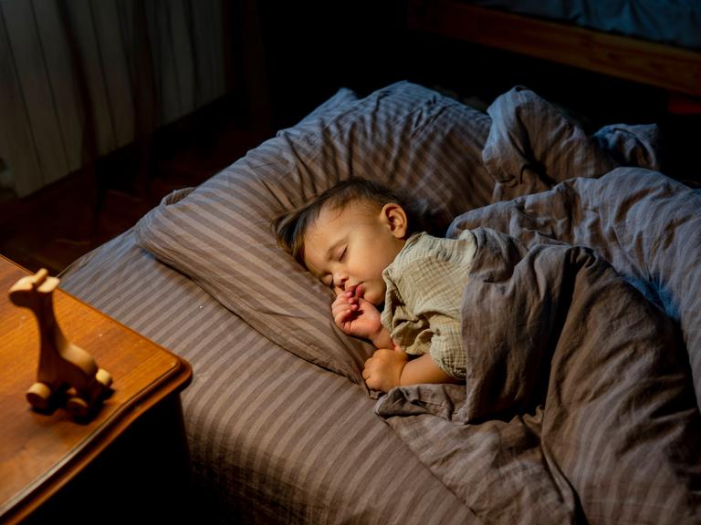 Ein schlafendes Baby liegt bei Nacht in seinem Bett.