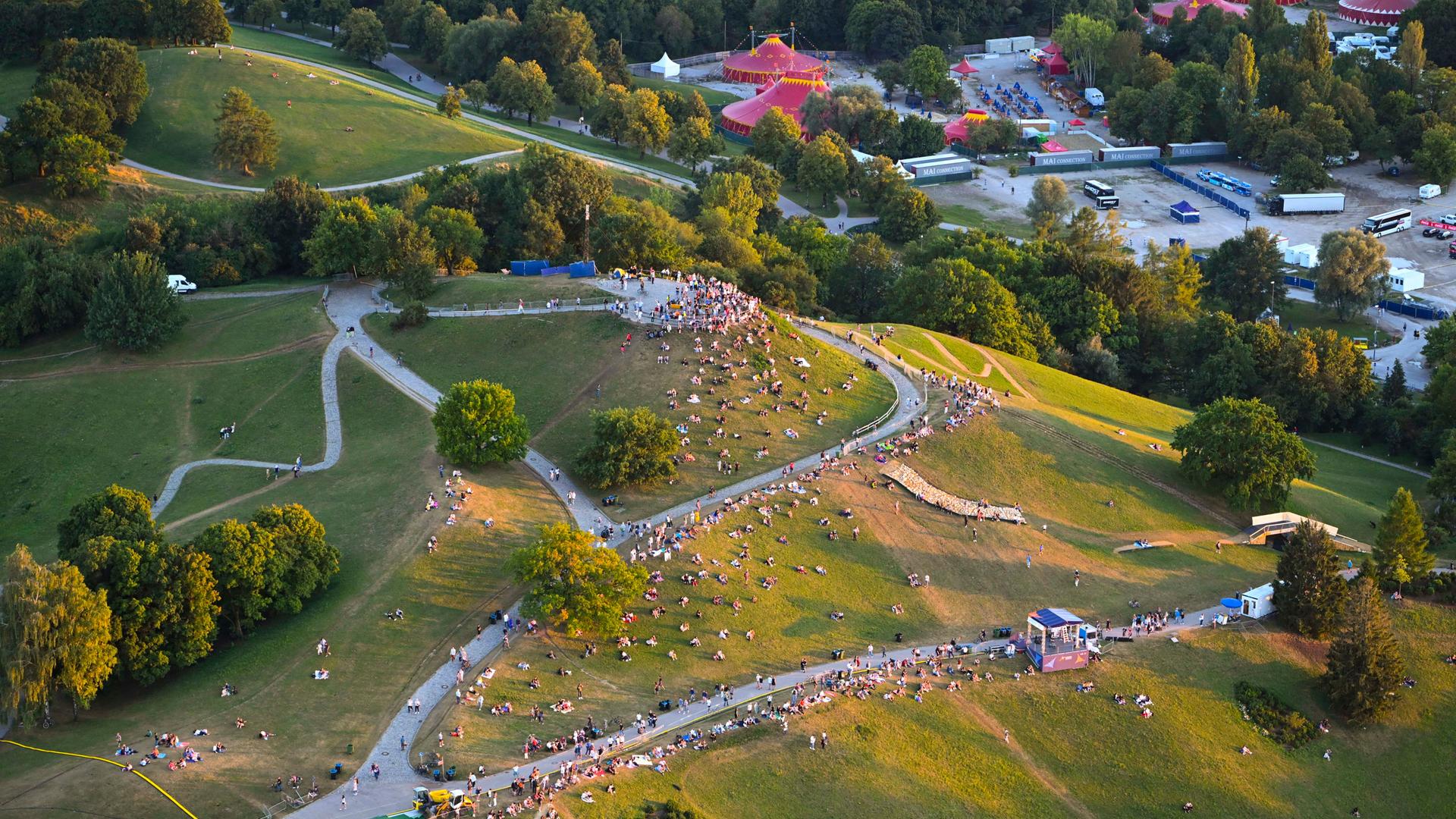 Grüne Hügel mit Menschen darauf: Blick auf den Olympiapark München.