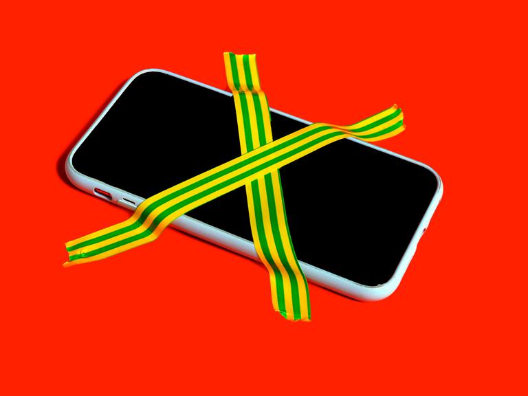 Farbenfrohes Stillleben eines Smartphones mit kreuzweise geklebten Klebebändern als Symbol für digitale Entgiftung und Handyverzicht