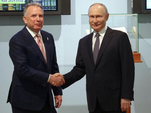 Der US-Sondergesandte Steve Witkoff und Russland Präsident Putin schütteln sich die Hand und blicken dabei in die Kamera.