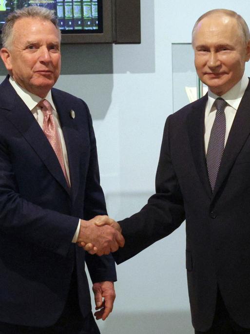 Der US-Sondergesandte Steve Witkoff und Russland Präsident Putin schütteln sich die Hand und blicken dabei in die Kamera.