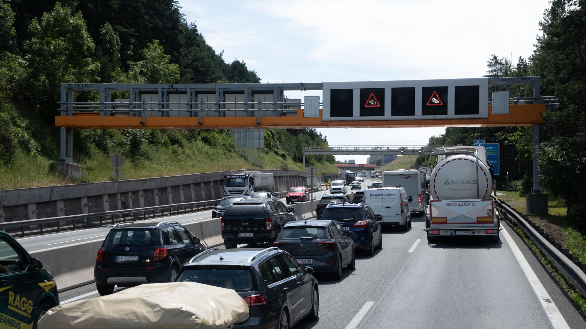 Viele Autos stauen sich auf der rechten Fahrbahnseite in einem Tal. Man sieht die Fahrzeuge von hinten.  