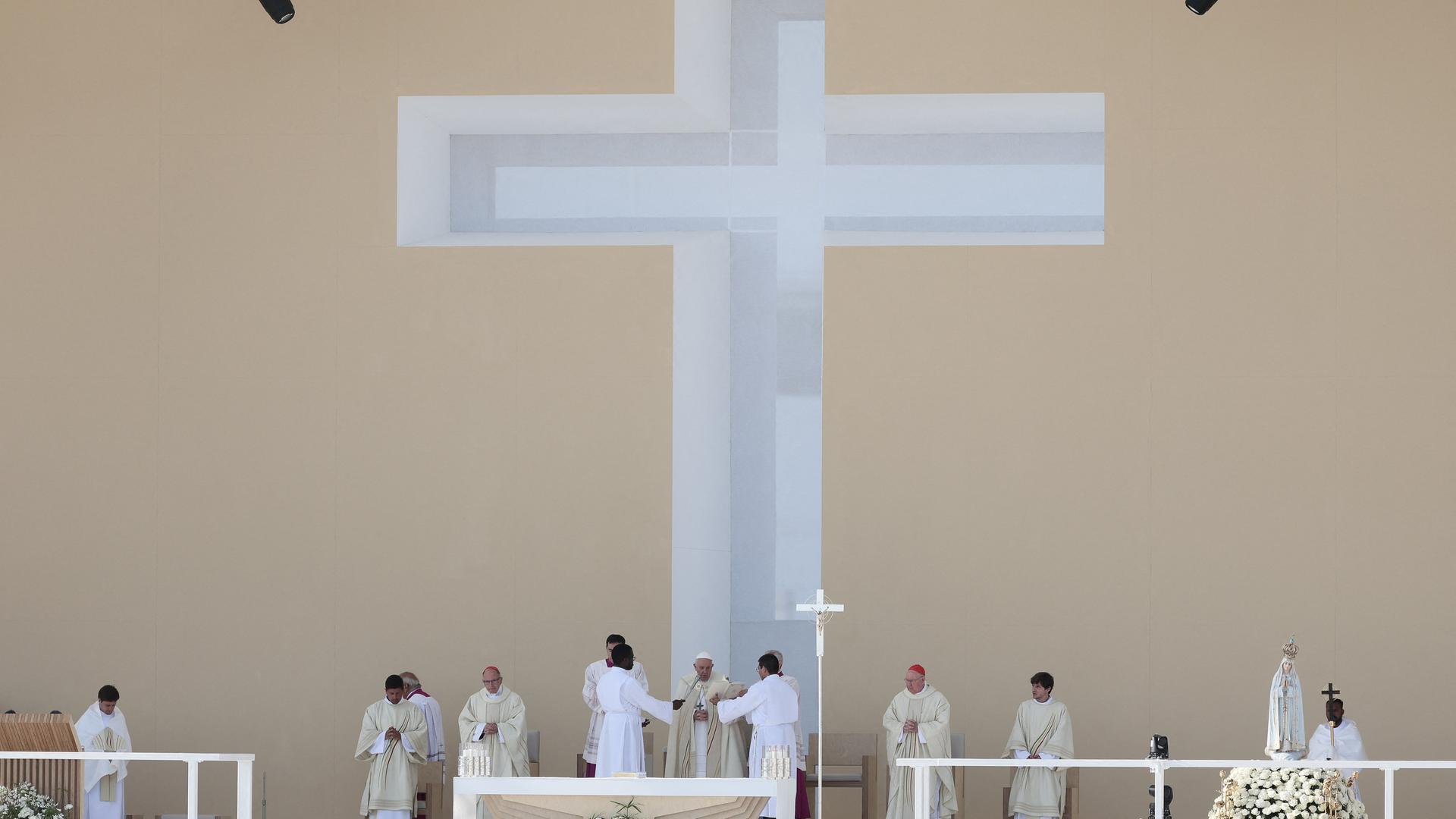 Papst Franziskus zelebiert die Abschlussmesse des Weltjugendtages in Lissabon. Er steht unter einem riesigen weißen Kreuz.