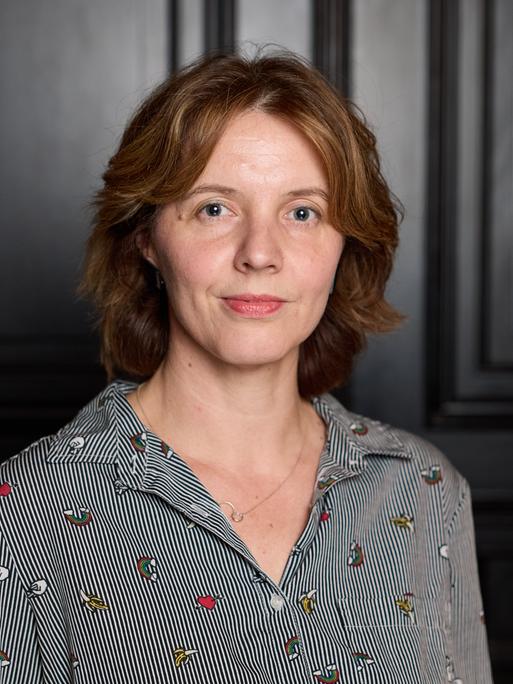 Portraitfoto von Peggy Mädler vor einer dunklen Tür Portraitfoto von Peggy Mädler vor einer dunklen Tür