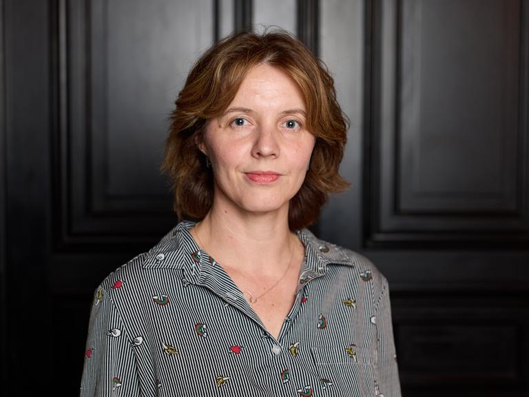 Portraitfoto von Peggy Mädler vor einer dunklen Tür Portraitfoto von Peggy Mädler vor einer dunklen Tür