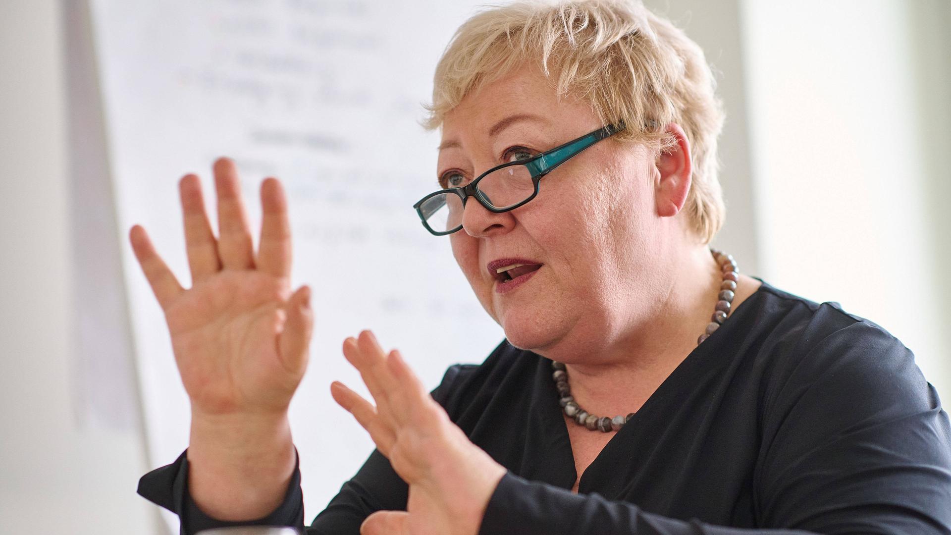 Porträt von Evelyn Zupke, die in einem Gespräch mit beiden Händen gestikuliert.
