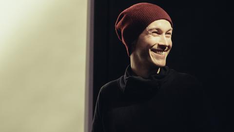 Der Drehbuchautor und Regisseur Benjamin Gutsche im Porträt. Er trägt eine Wollmütze und einen schwarzen Rollkragenpulli und lacht. Der Drehbuchautor und Regisseur Benjamin Gutsche im Porträt. Er trägt eine Wollmütze und einen schwarzen Rollkragenpulli und lacht.