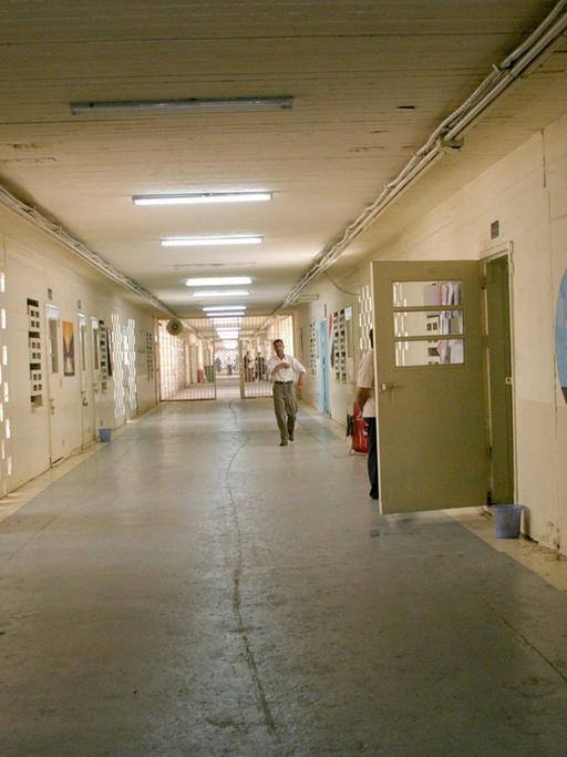 Ein Gang im Gefängnis Abu Ghraib mit gelbgestrichenen Wänden und rechts einer geöffneten Tür.