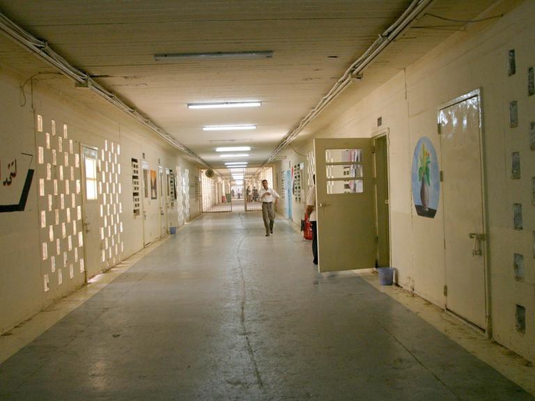 Ein Gang im Gefängnis Abu Ghraib mit gelbgestrichenen Wänden und rechts einer geöffneten Tür.