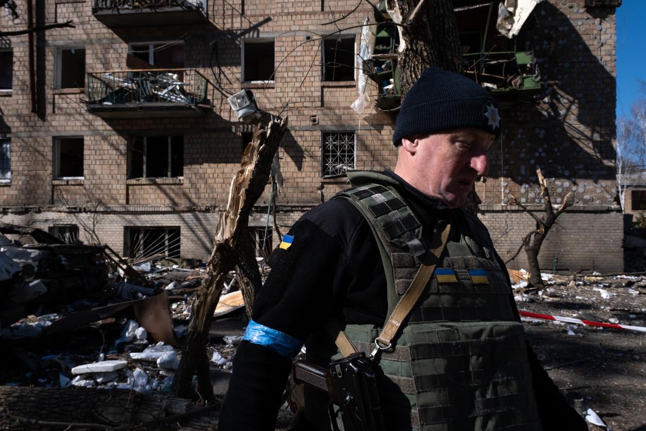 Ein ukrainischer Soldat läuft vor einem zerstört Wohnblock entlang.