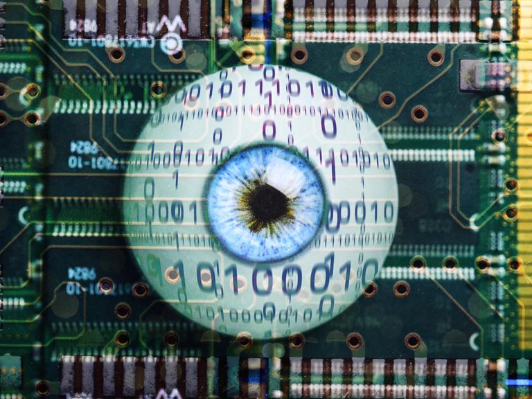 Symbolbild für Künstliche Intelligenz: Ein künstliches Auge mit Binärcode liegt auf einer Computerplatine.