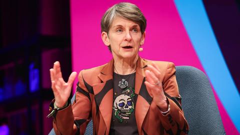 Laura McAllister, Vizepräsidentin der UEFA, spricht bei einem Podiumsgespräch vor einer rosa-blauen Wand