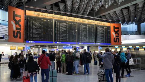 Menschen stehen vor einer Anzeigetafel mit gestrichenen Flügen der Lufthansa am Frankfurter Flughafen.