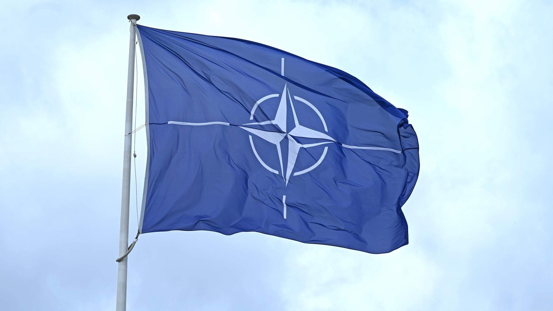 Eine Flagge mit dem Logo der Nato weht im Wind.