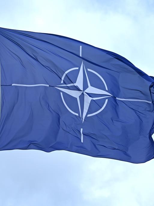 Eine Flagge mit dem Logo der NATO weht im Wind.