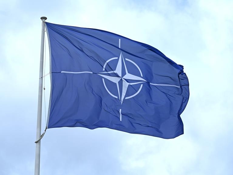 Eine Flagge mit dem Logo der NATO weht im Wind.