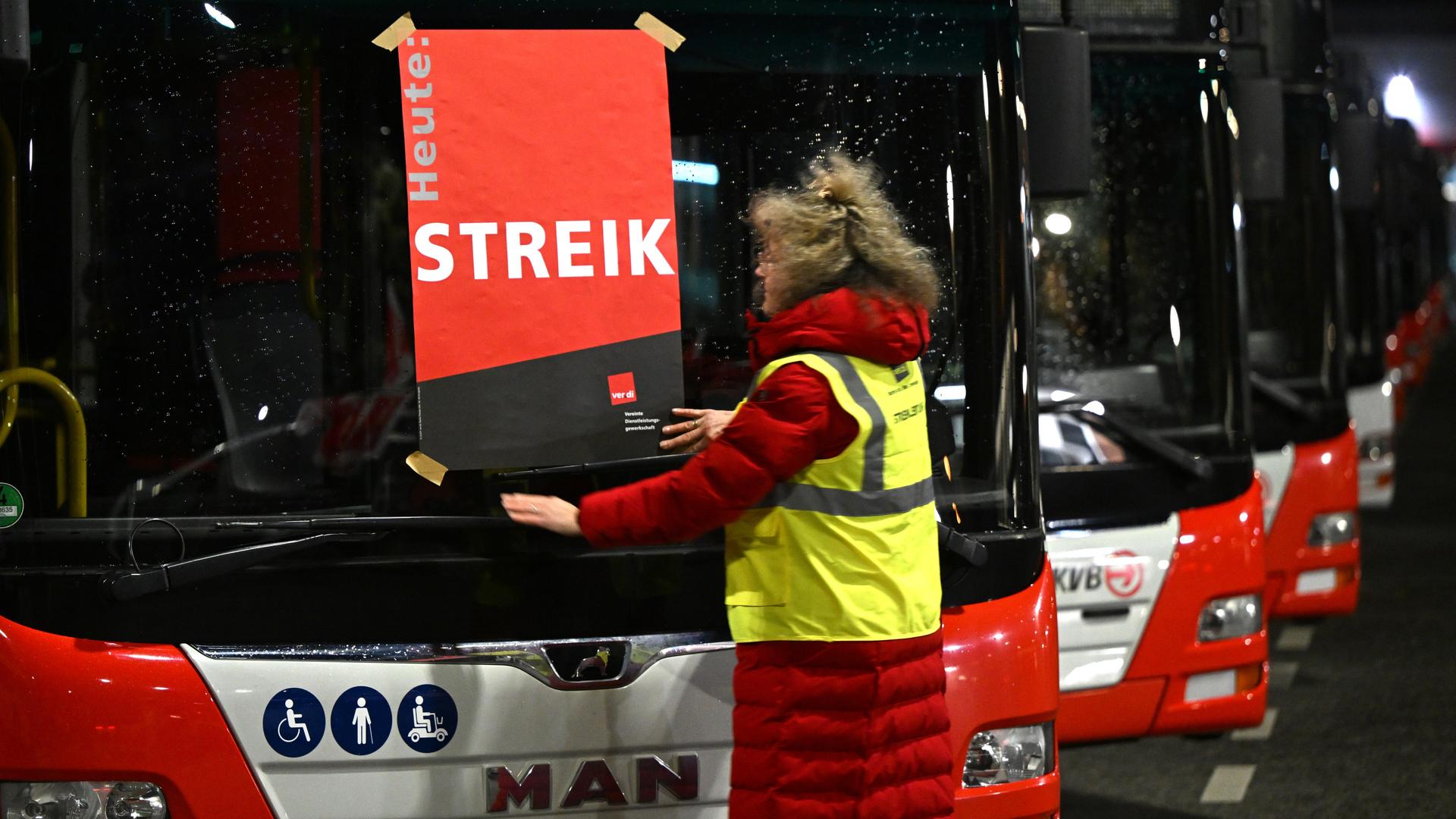 Köln: Eine Mitarbeiterin klebt ein Plakat mit der Aufschrift "Streik" auf die Frontscheibe eines Busses.