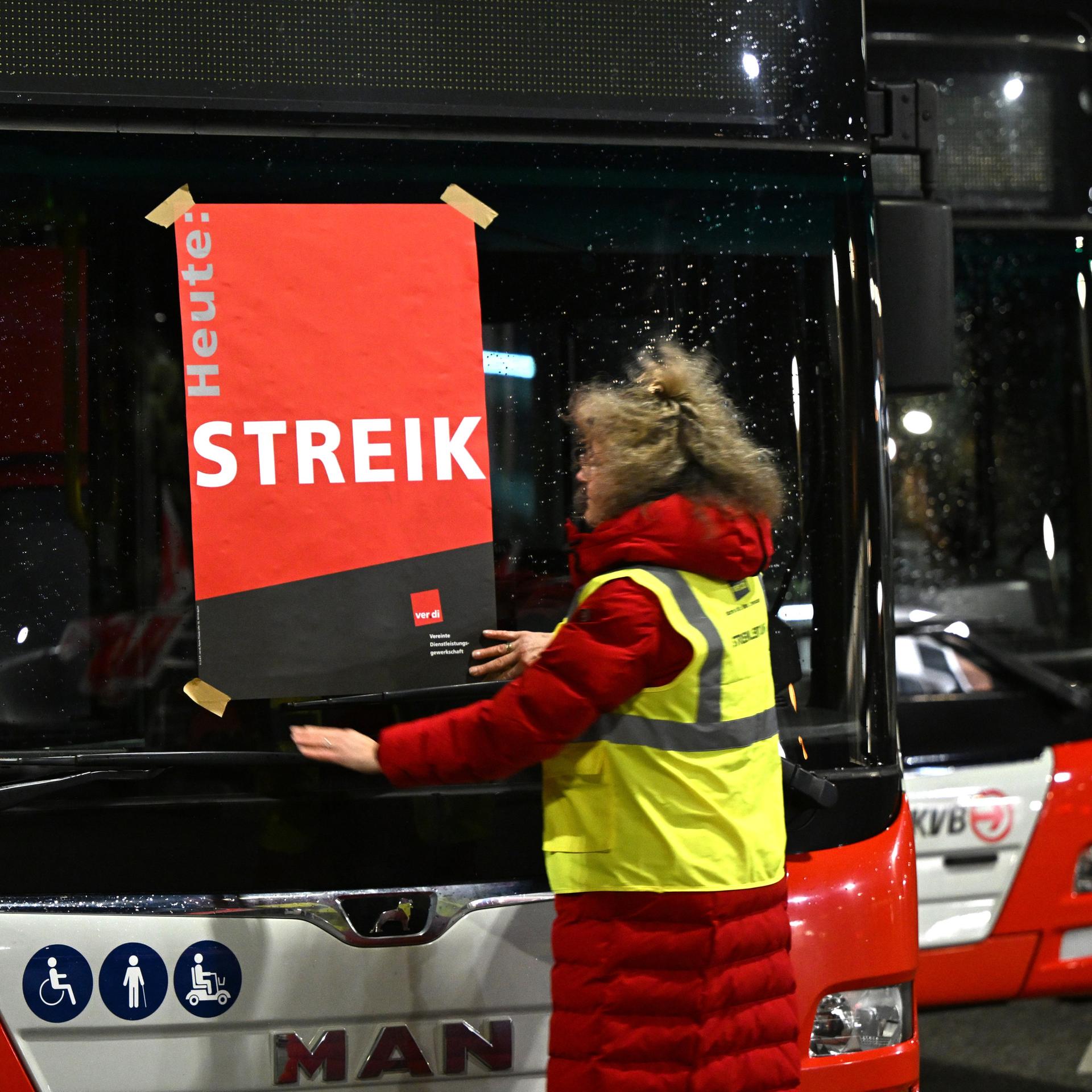 Köln: Eine Mitarbeiterin klebt ein Plakat mit der Aufschrift "Streik" auf die Frontscheibe eines Busses.  