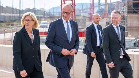 Der Vorstandsvorsitzende von Saarstahl Dillinger, Stefan Rauber (r-l), geht mit Bundeskanzler Friedrich Merz (CDU) und der saarländischen Ministerpräsidentin Anke Rehlinger (SPD) über die Baustelle des neuen Werks.