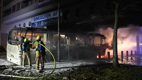 Einsatzkräfte der Feuerwehr löschen in der Silvesternacht an der Sonnenallee im Bezirk Neukölln einen brennenden Bus, der von Unbekannten angezündet worden war.