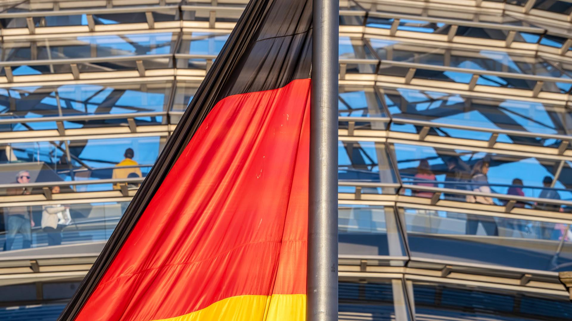 Deutschlandfahne im Abendlicht vor der Reichstagskuppel Deutschlandfahne im Abendlicht vor der Reichstagskuppel