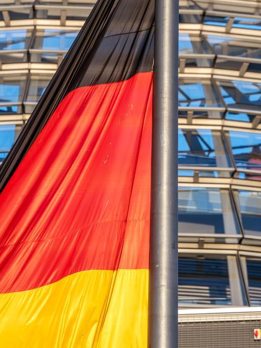 Deutschlandfahne im Abendlicht vor der Reichstagskuppel Deutschlandfahne im Abendlicht vor der Reichstagskuppel