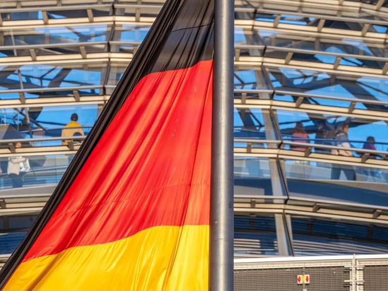 Deutschlandfahne im Abendlicht vor der Reichstagskuppel Deutschlandfahne im Abendlicht vor der Reichstagskuppel