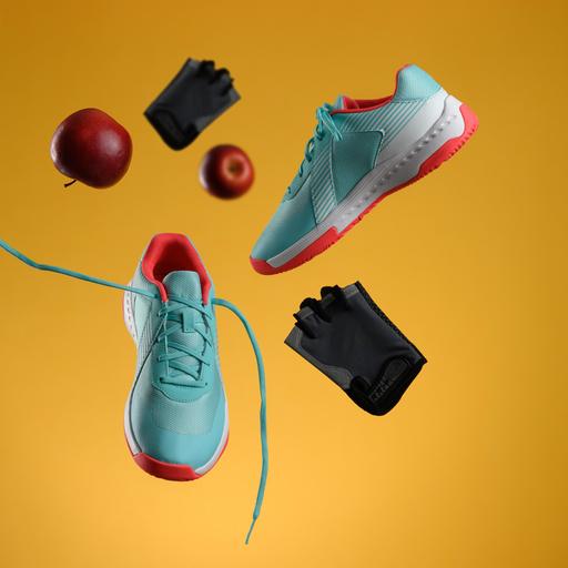 Ein roter Apfel, Handschuhe und ein Paar Turnschuhe fliegen durch die Luft. 