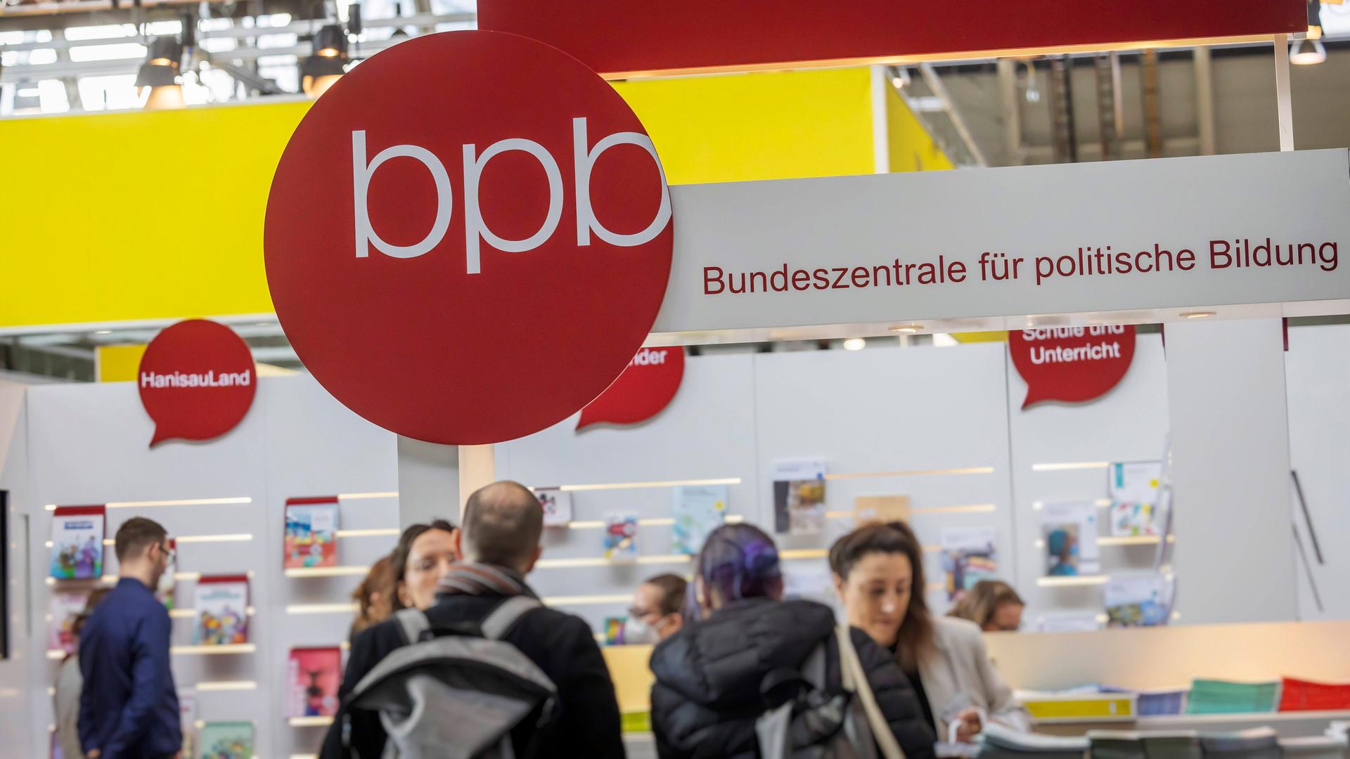 Das Logo der Bundeszentrale für politische Bildung, BPB, ist auf der Messe Didacta in Stuttgart zu sehen. An dem Stand stehen mehrere Menschen. Das Logo der Bundeszentrale für politische Bildung, BPB, ist auf der Messe Didacta in Stuttgart zu sehen. An dem Stand stehen mehrere Menschen.
