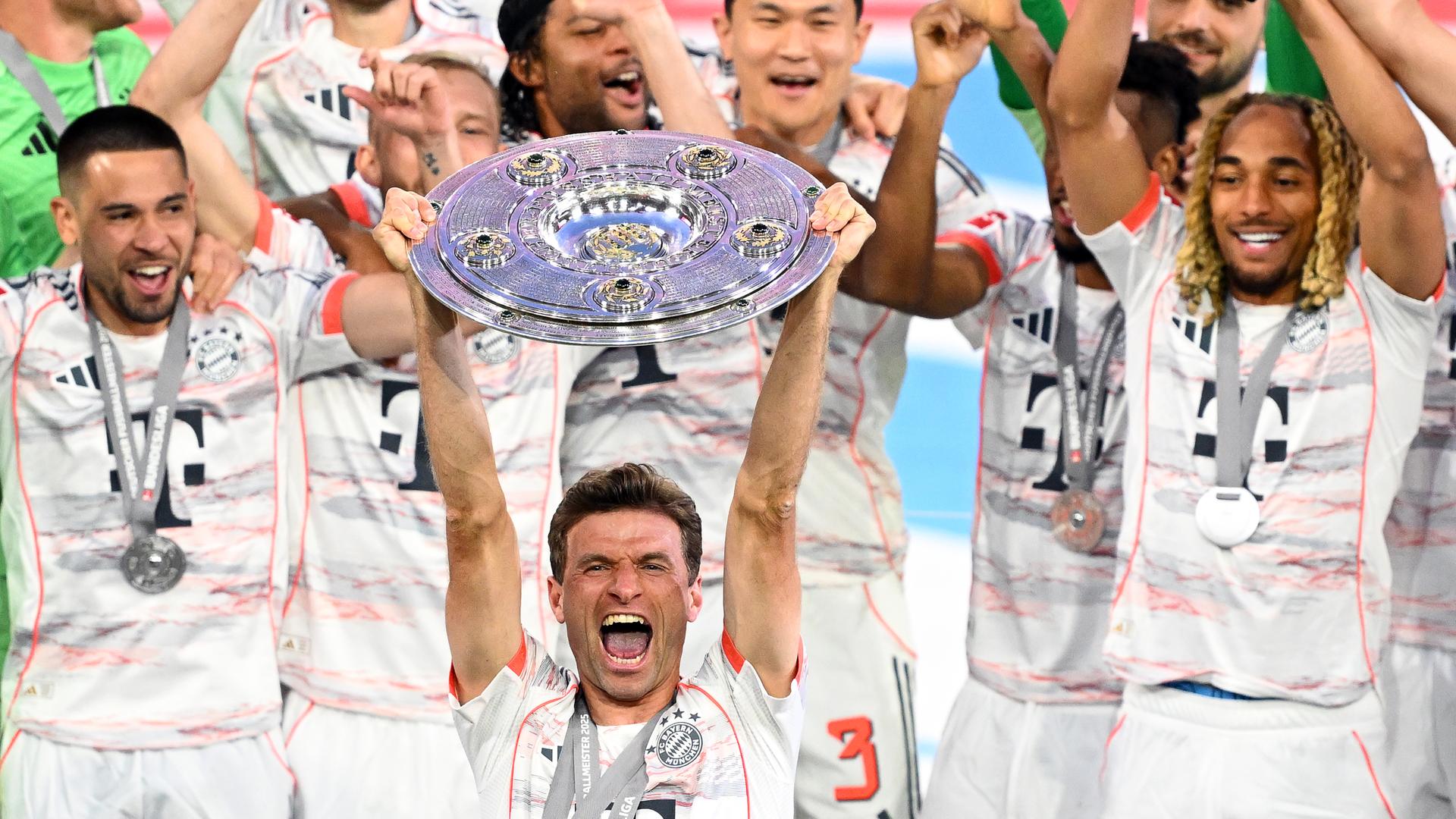 Thomas Müller jubelt mit der Meisterschale, im Hintergrund weitere Bayern-Spieler. Thomas Müller jubelt mit der Meisterschale, im Hintergrund weitere Bayern-Spieler.
