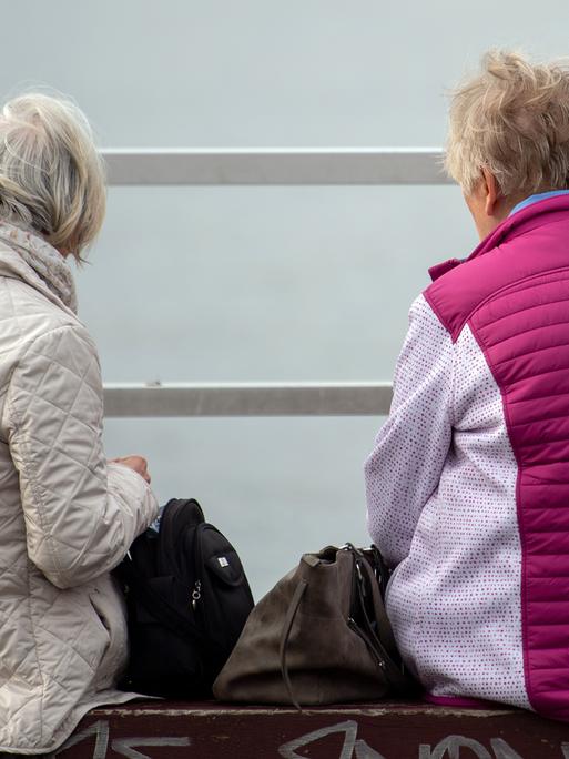 Zwei ältere Frauen sitzen auf einer Bank am Wannsee.