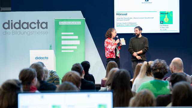 Eine Frau und ein Mann mit Mikrofonen auf einer Bühne von Deutschlandfunk Nova bei der Bildungsmesse didacta 2026 in Köln
