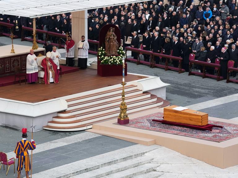 Ein bild von der Trauer-Feier: Man sieht einen Altar. Davor ist der Sarg von Papst Benedikt.