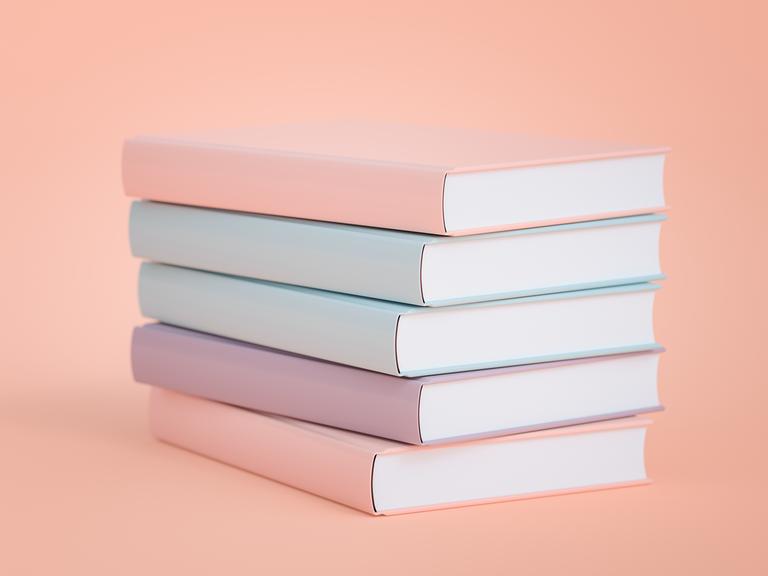Pastellige gleichförmige Bücher auf einem Stapel.