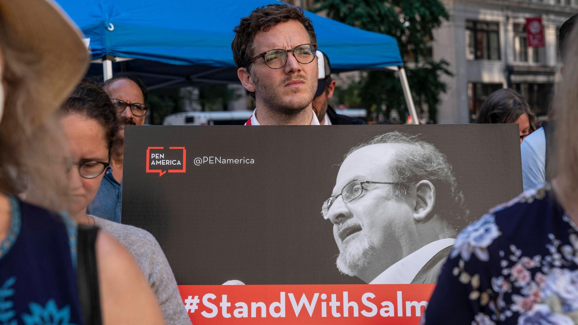 Ein Aktivist bei der Solidaritäts-Rally für Salman Rushdie des PEN America vor der New York Library hält ein Schild hoch, auf dem "PEN America #STANDWITHSALMAN" zu lesen ist. Ein Aktivist bei der Solidaritäts-Rally für Salman Rushdie des PEN America vor der New York Library hält ein Schild hoch, auf dem "PEN America #STANDWITHSALMAN" zu lesen ist.