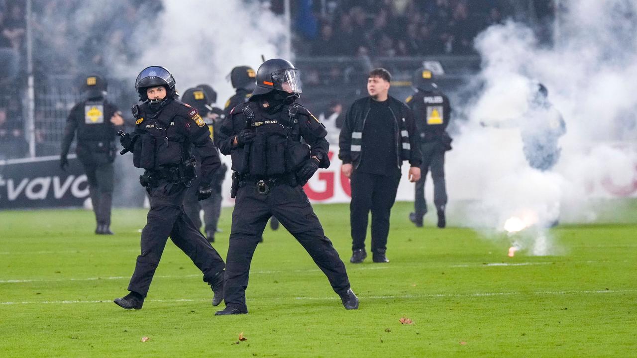 Polizisten sichern das Spielfeld nach Pyroattacken von den Rängen.