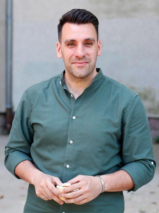 Engin Çatik lächelt in die Kamera. Er trägt ein salbeigrünes Hemd und hat kurzes, dunkelbraunes Haar.