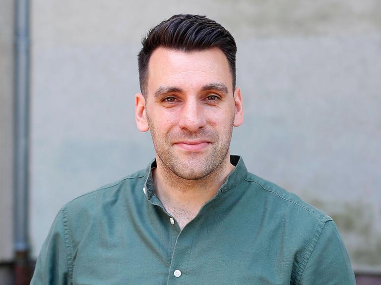 Engin Çatik lächelt in die Kamera. Er trägt ein salbeigrünes Hemd und hat kurzes, dunkelbraunes Haar.