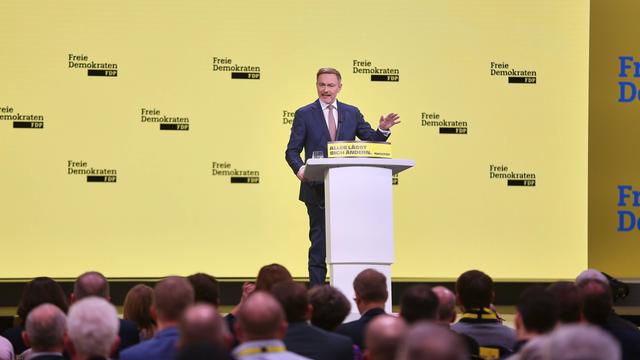 Potsdam: FDP-Chef Lindner spricht beim Parteitag. Er steht auf der Bühne an einem Rednerpult und gestikuliert mit der linken Hand. Er trägt Anzug und Krawatte. Im Vordergrund sind die Delegierten zu sehen.