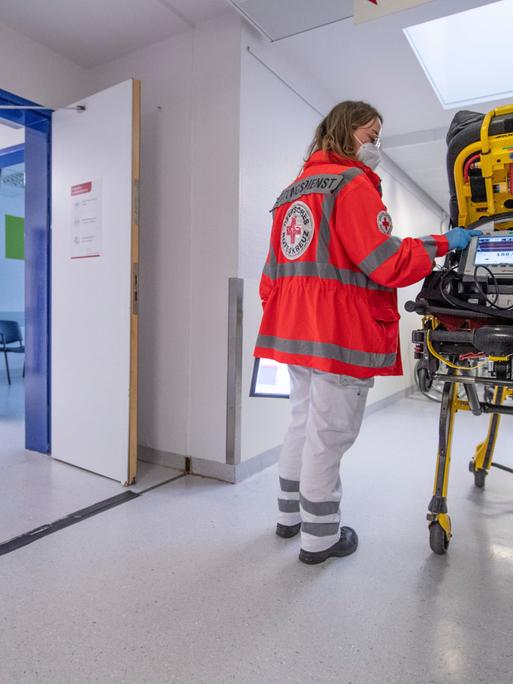 Eine Notfallsanitäterin des Deutschen Roten Kreuzes (DRK), schiebt eine Seniorin nach einem Schlaganfall auf einer Trage in die Notaufnahme eines Krankenhauses und wartet auf die Ãbergabe an die diensthabende Ãrztin