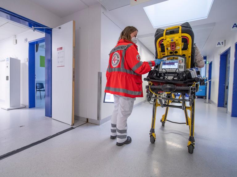 Eine Notfallsanitäterin des Deutschen Roten Kreuzes (DRK), schiebt eine Seniorin nach einem Schlaganfall auf einer Trage in die Notaufnahme eines Krankenhauses und wartet auf die Ãbergabe an die diensthabende Ãrztin