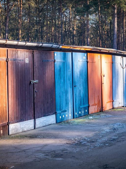 Ein Bild von Gararen aus DDR-Zeiten in Hennigsdorf im Bundesland Brandenburg. Sie scheinen aus Holz gefertigt zu sein. Die Tore sind bunt gestrichen, aber der Lack löst sich.