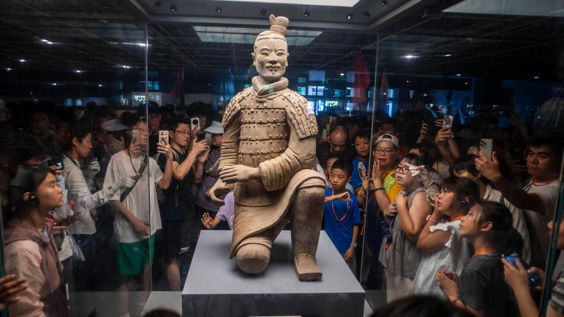 Xi’an, Provinz Shaanxi, USA: Besucher fotografieren einen Tonkrieger aus der Terrakotta-Armee im Mausoleum von Qin Shi Huang, dem ersten Kaiser Chinas