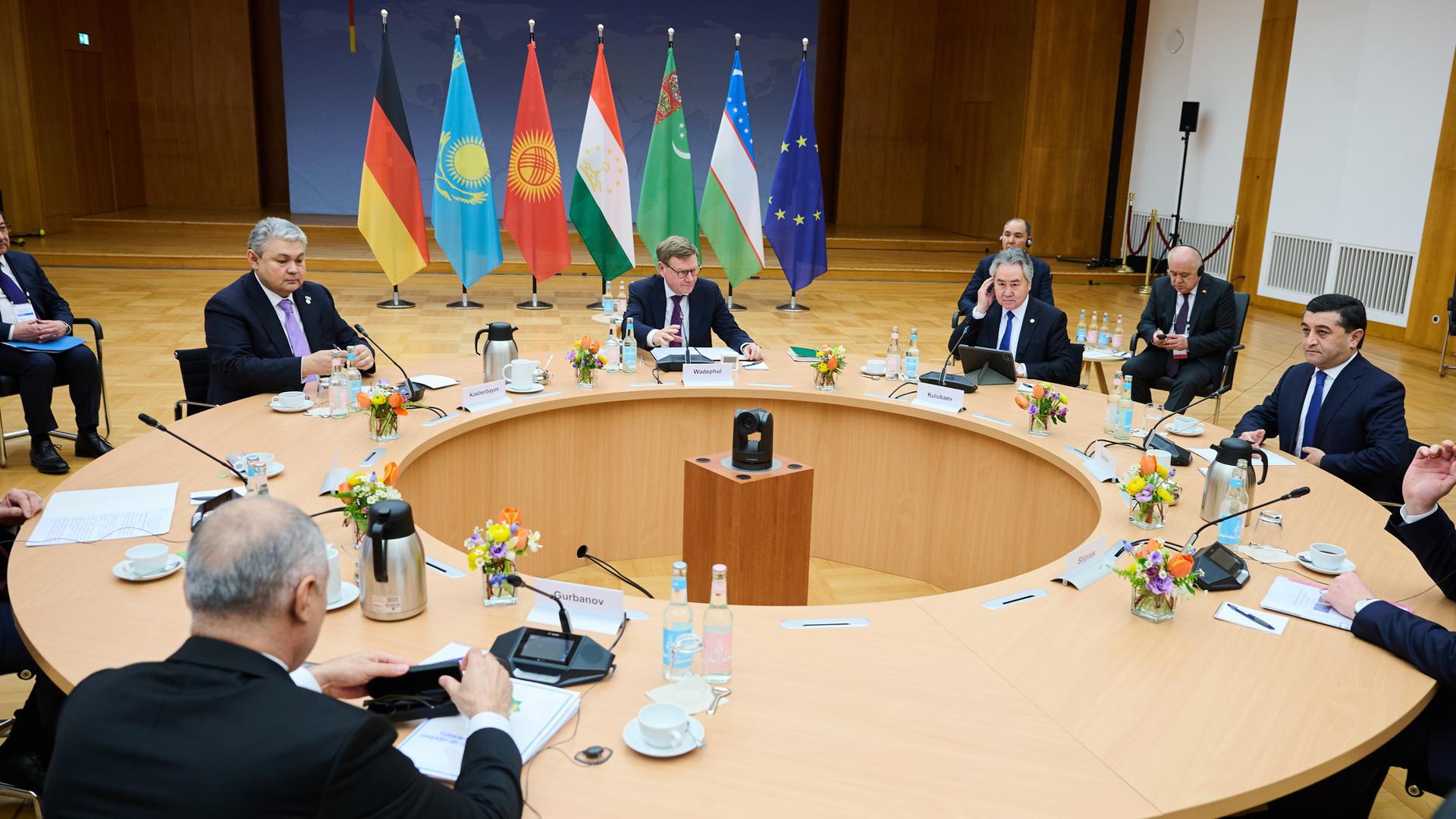 Die Minister sitzen an einem runden Tisch in einem großen Raum. Wadephul spricht gerade und gestikuliert mit der rechten Hand. Dahinter stehen nebeneinander die Flaggen der Gaststaaten.