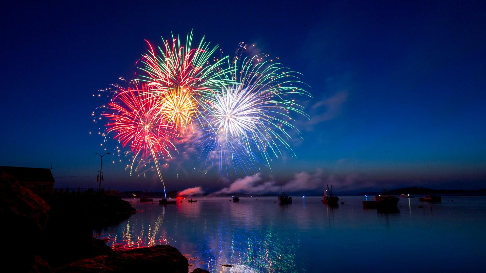 Wir sehen ein buntes Feuerwerk über einem Fluß